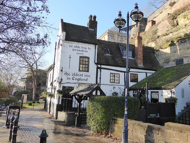 A stone pub, painted while, nestled at the foot of some sandstone cliffs